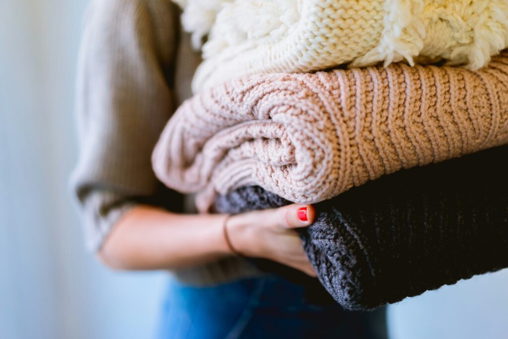 Strickpullover in den Händen, geeignet zum Waschen bei 30 Grad
